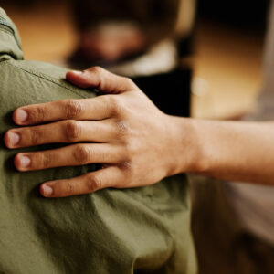 Hand of young supportive man consoling his friend with post traumatic syndrome