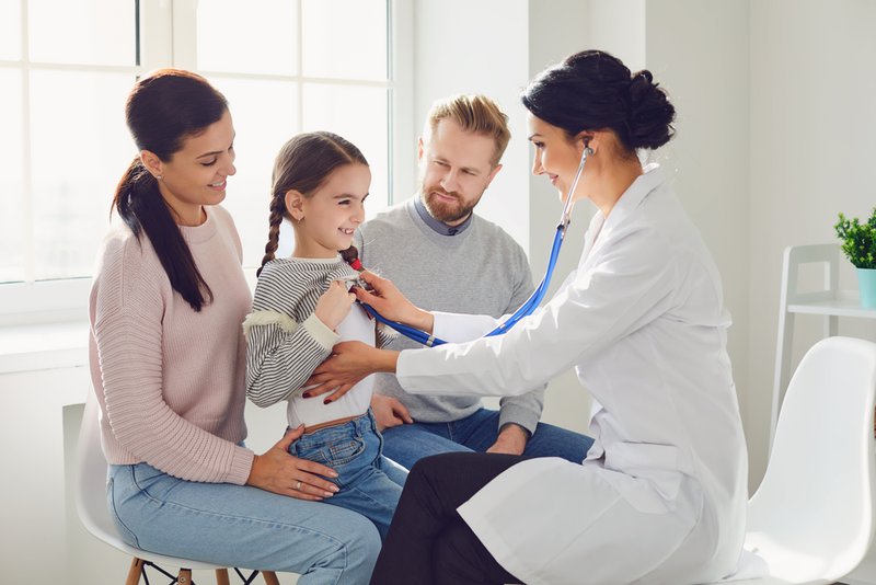 Female family doctor with listening to a young girl's heartbeat