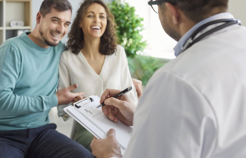 Male family doctor talking to a happy couple